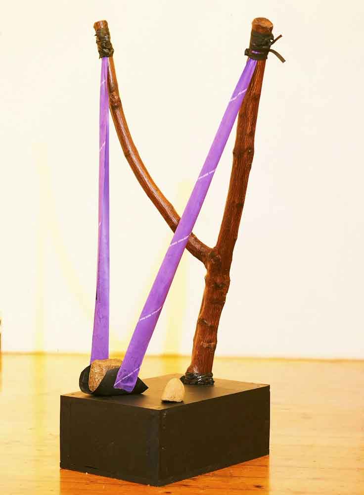 A photo of a giant slingshot with a rock placed in the rubber band of the slingshot