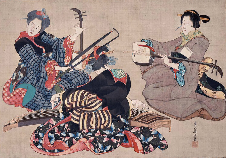 Three young women playing percussion instruments, the centre woman is facing towards the back so you cannot see her face