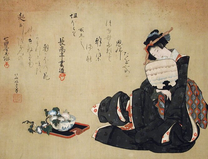 A young woman holding a fan with a bowl of flowers next to her, there is Japanese script to her left