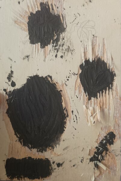 A woodblock with a carved heart, grass, a gate and blossom in different parts. These are all painted black (seeming almost stained)