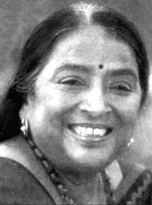 Photo of a late middle aged Indian woman, she is wearing a bindi and is smiling widely